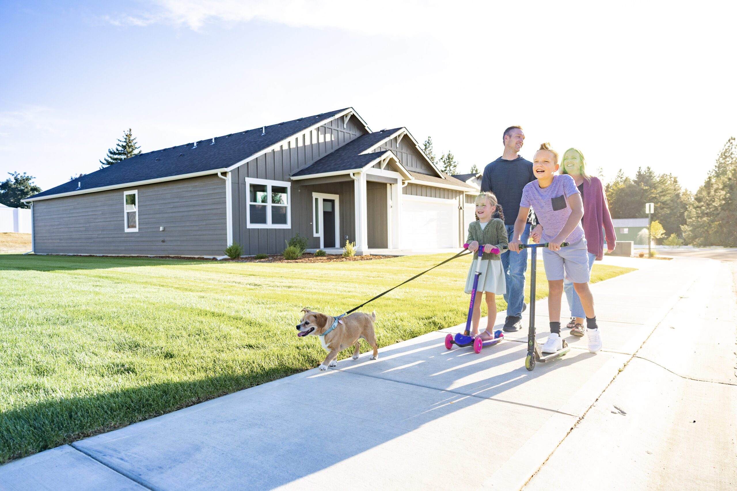 Photo of a family of four and their small dog on a sunset walk past their Architerra Home in Deer Park, Washington.