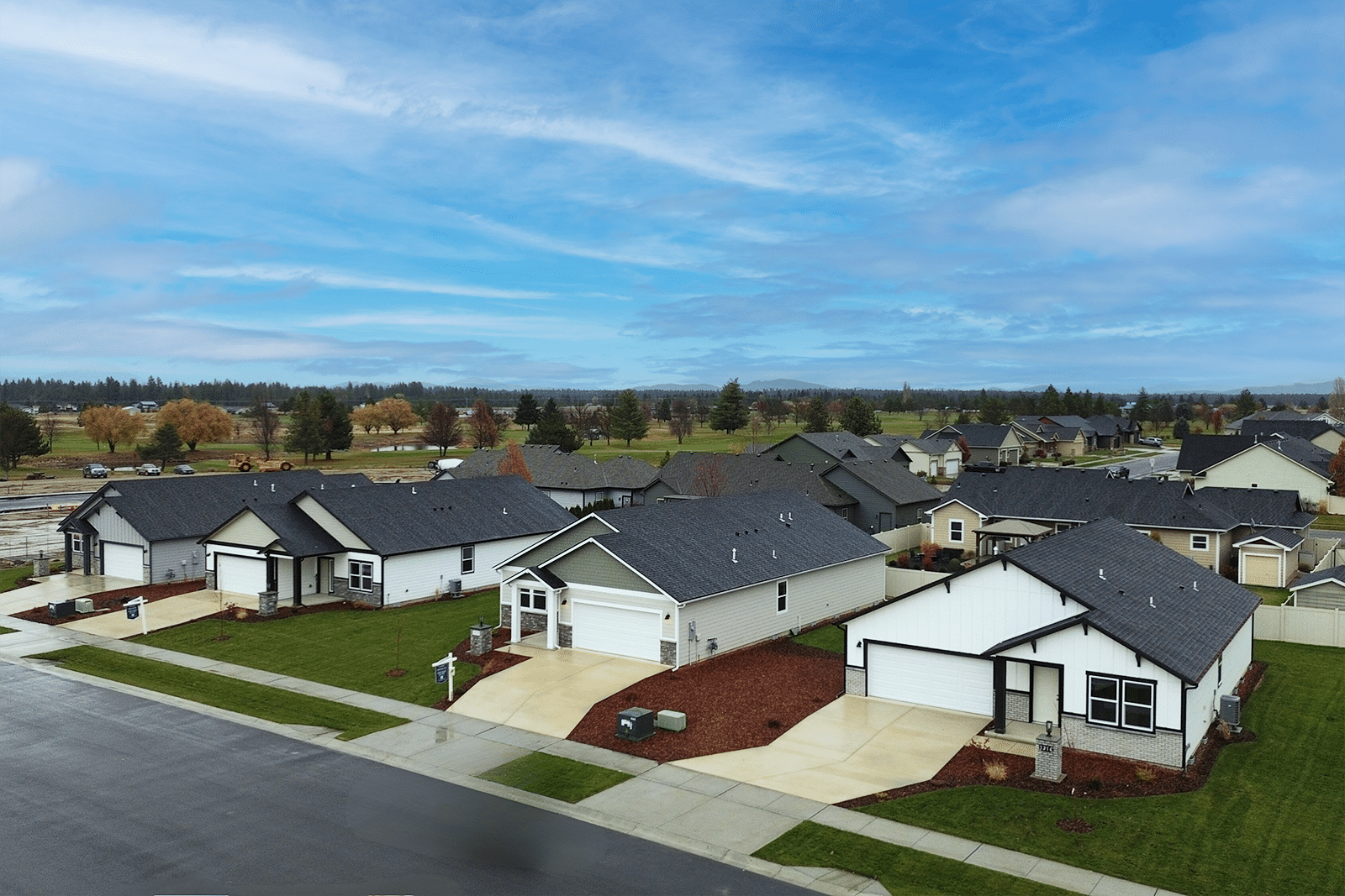 Mountain View Meadows North High Desert Drive displayed from a drone high angle in line with the roofs. Pine tree and clear skies are visible in this community shot.