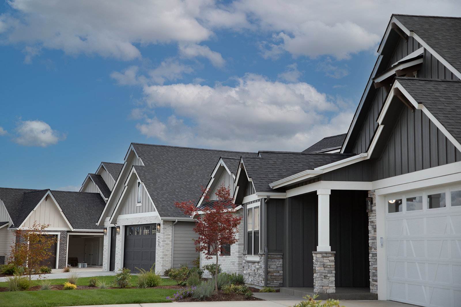 Profile angle of three luxury homes in The Enclave community by Architerra. Lawns are freshly mowed and it is dusk.